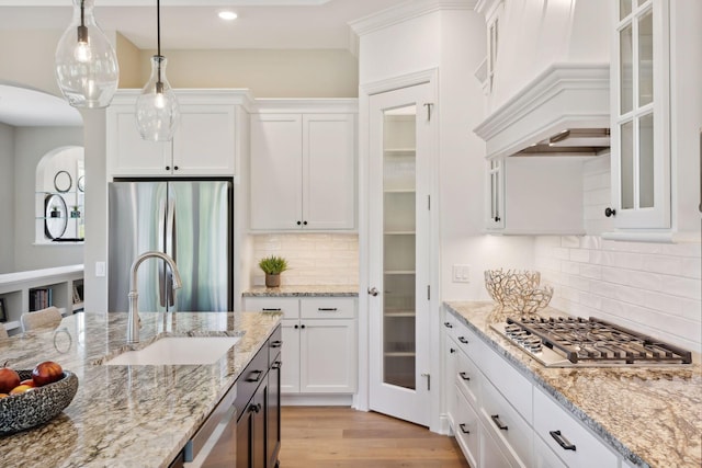 kitchen with sink, white cabinetry, backsplash, stainless steel appliances, and decorative light fixtures