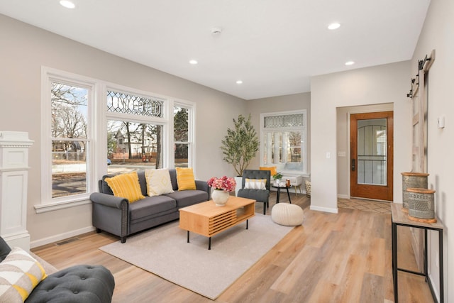 living area with baseboards, a barn door, light wood-type flooring, and recessed lighting