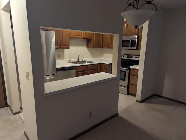 kitchen featuring sink, kitchen peninsula, stainless steel appliances, and hanging light fixtures