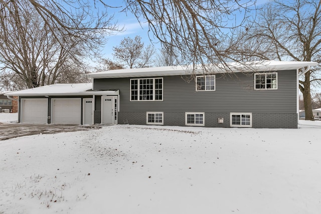 snow covered house featuring a garage