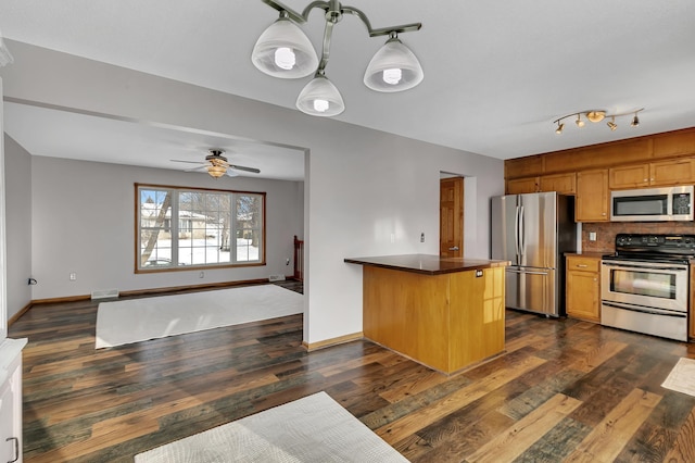 kitchen with dark hardwood / wood-style flooring, tasteful backsplash, stainless steel appliances, ceiling fan, and hanging light fixtures