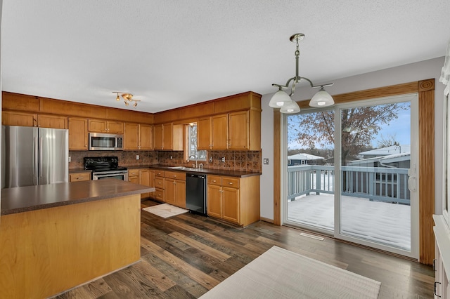 kitchen with sink, dark hardwood / wood-style floors, tasteful backsplash, decorative light fixtures, and stainless steel appliances