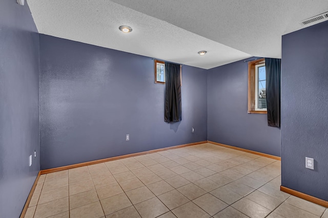 tiled empty room featuring a textured ceiling