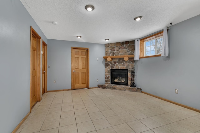 unfurnished living room featuring a stone fireplace, light tile patterned floors, and a textured ceiling