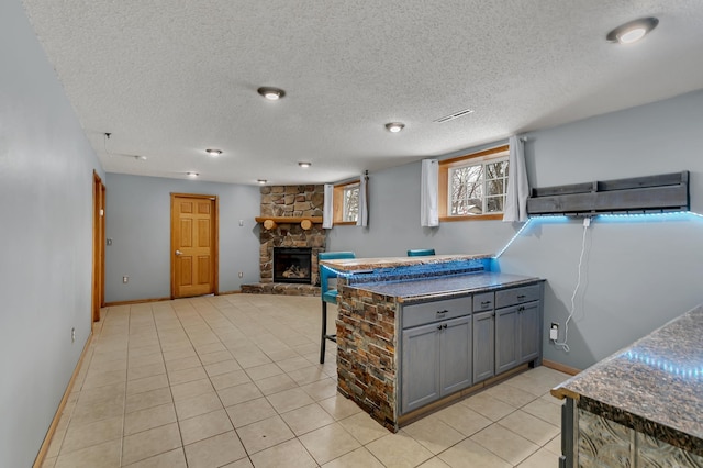 kitchen featuring a fireplace, light tile patterned floors, a textured ceiling, and gray cabinets