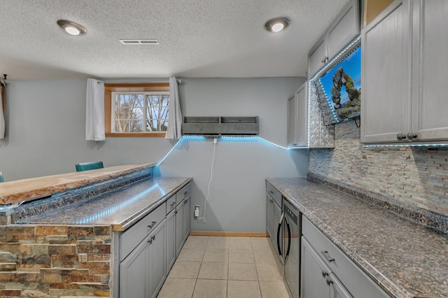 kitchen with gray cabinets, light tile patterned floors, and a textured ceiling