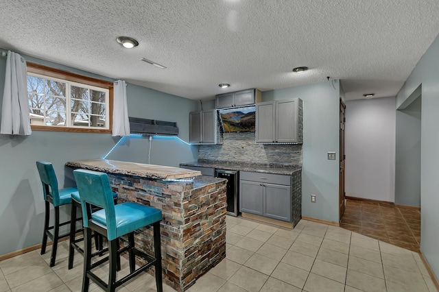 kitchen with wine cooler, kitchen peninsula, a breakfast bar area, gray cabinets, and light tile patterned floors