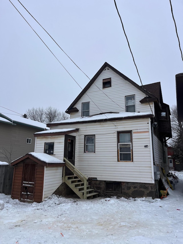 snow covered rear of property with a storage shed