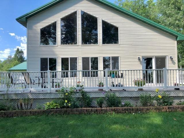 back of property with a lawn and a deck