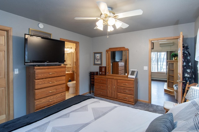 bedroom featuring a wall mounted air conditioner, a baseboard radiator, ensuite bath, and ceiling fan