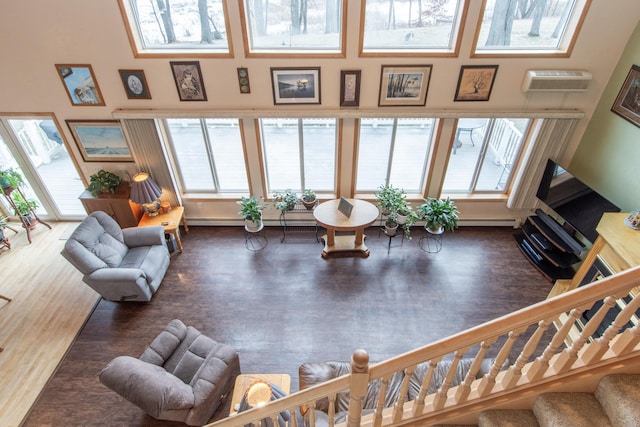 living room featuring dark hardwood / wood-style flooring, a wall unit AC, and a healthy amount of sunlight