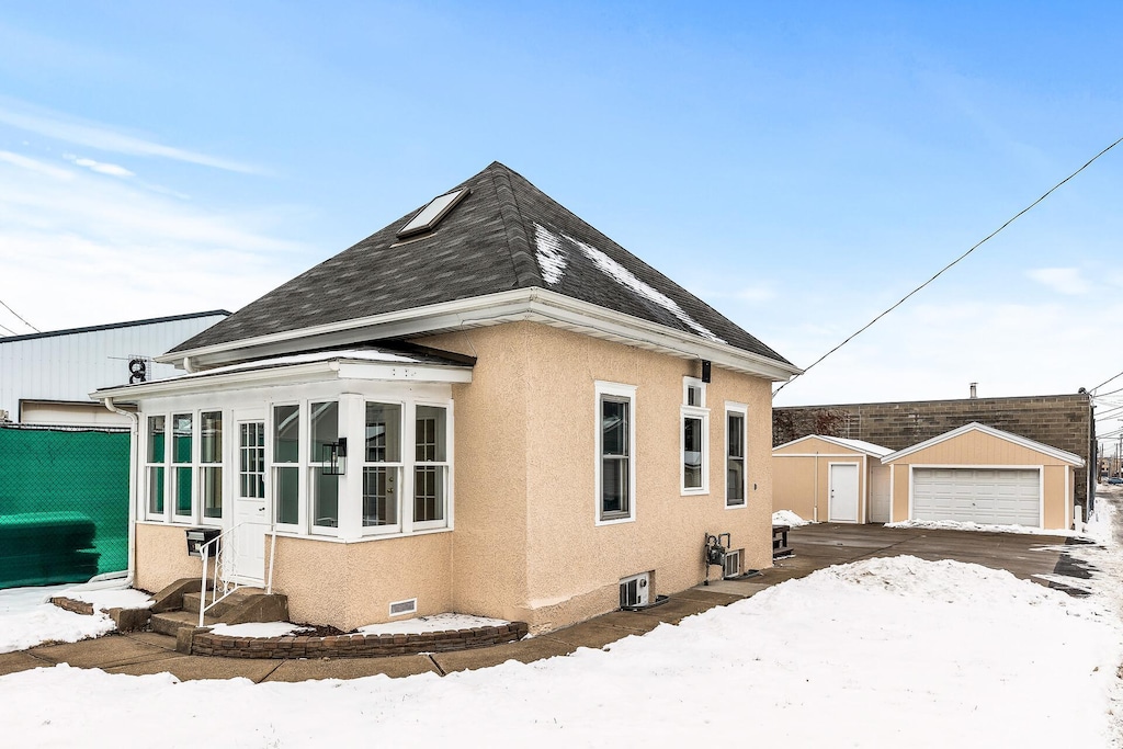 snow covered property featuring a garage and an outdoor structure