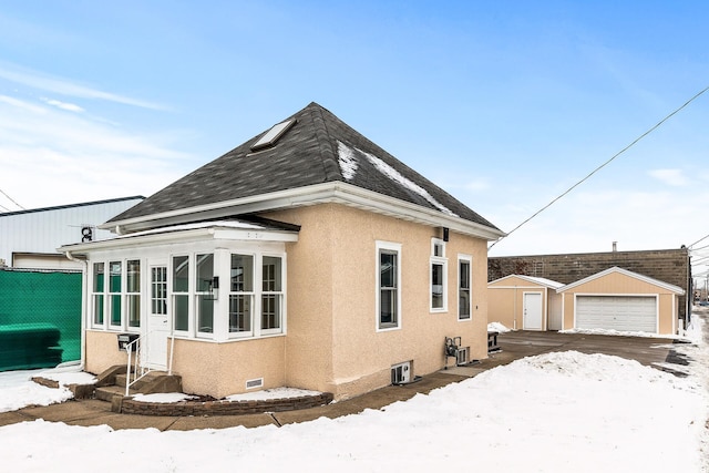 snow covered property featuring a garage and an outdoor structure