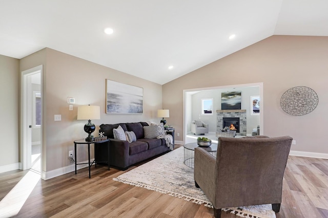 living room featuring a fireplace, light wood-type flooring, and lofted ceiling