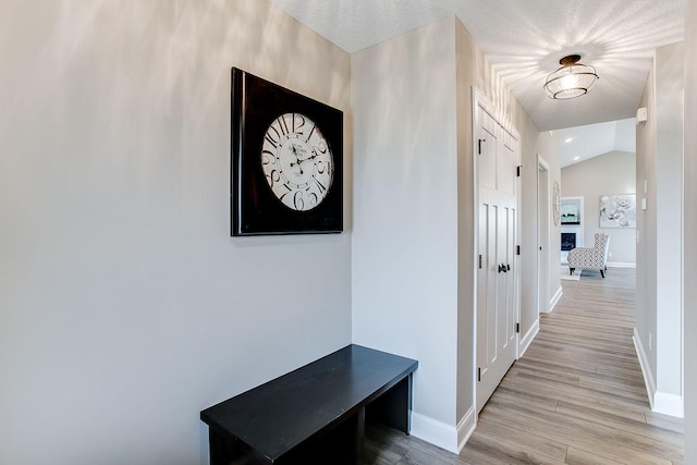 hall featuring light hardwood / wood-style flooring and lofted ceiling