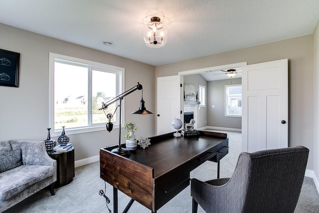 carpeted home office with a textured ceiling, a brick fireplace, and ceiling fan