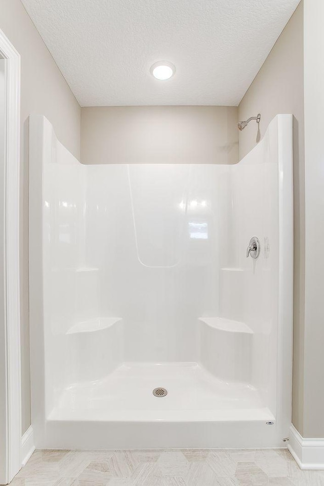 bathroom with a shower and a textured ceiling