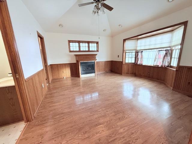 unfurnished living room featuring light wood-type flooring, vaulted ceiling, and ceiling fan