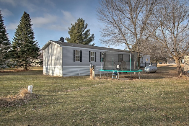 rear view of property featuring a yard and a trampoline