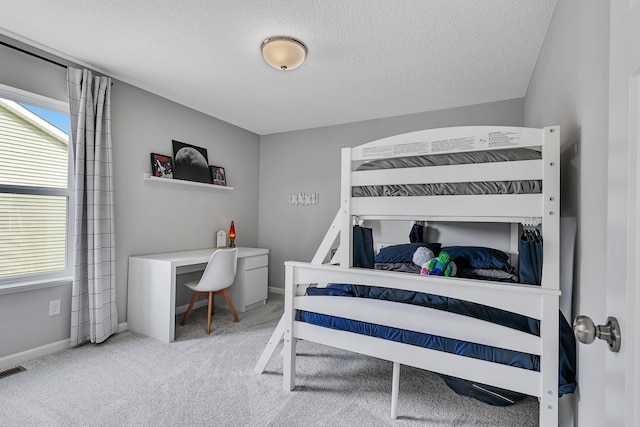 bedroom with light colored carpet and a textured ceiling