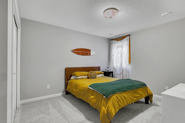 bedroom featuring a textured ceiling, light colored carpet, and a closet