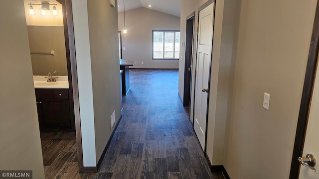 hallway featuring dark hardwood / wood-style flooring, vaulted ceiling, and sink