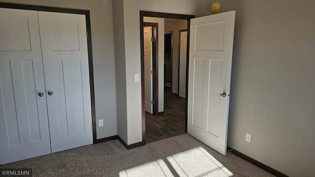 unfurnished bedroom featuring dark carpet and a closet