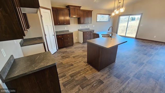 kitchen featuring dark hardwood / wood-style flooring, dark brown cabinetry, a kitchen island with sink, sink, and decorative light fixtures