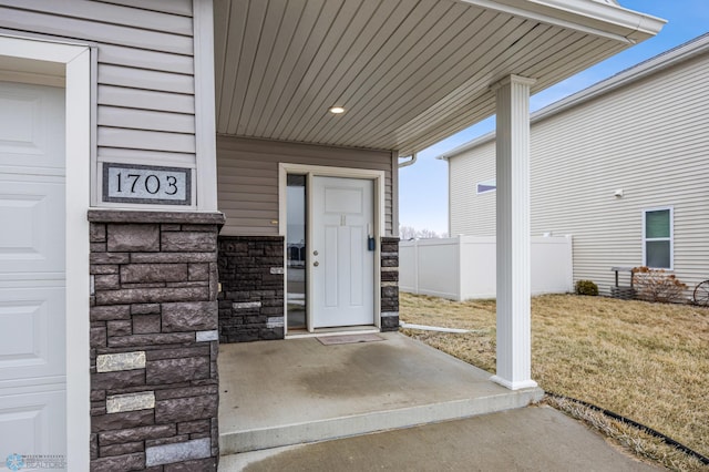 doorway to property featuring covered porch and a lawn