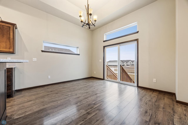 empty room featuring dark wood-type flooring and a notable chandelier