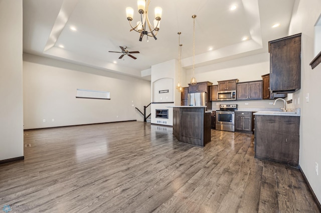 kitchen with decorative light fixtures, a kitchen island, appliances with stainless steel finishes, and a tray ceiling