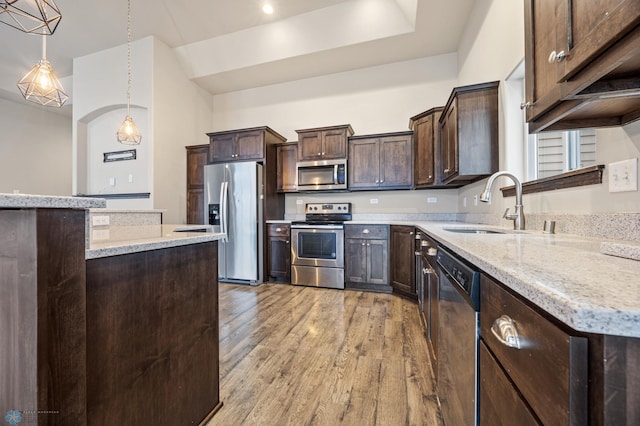 kitchen featuring sink, light wood-type flooring, decorative light fixtures, dark brown cabinetry, and stainless steel appliances