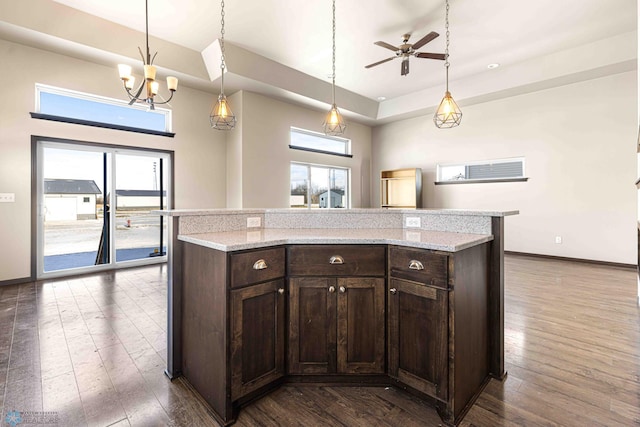 kitchen with pendant lighting, dark hardwood / wood-style flooring, a kitchen island, and dark brown cabinets