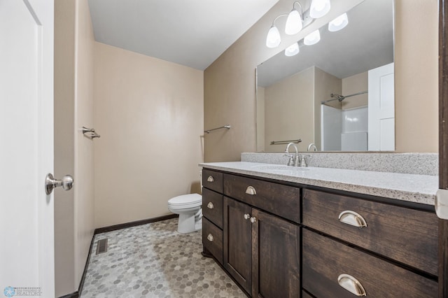 bathroom featuring toilet, vanity, and walk in shower