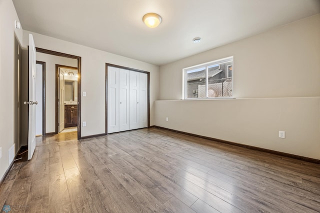 unfurnished bedroom featuring light wood-type flooring, ensuite bath, and a closet