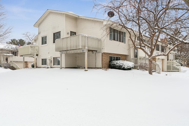 snow covered back of property with a balcony