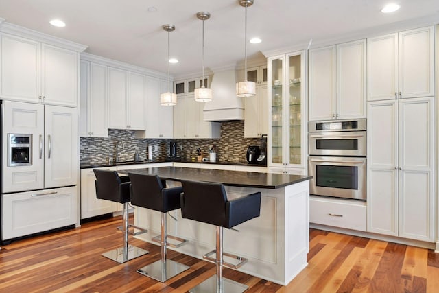 kitchen featuring white cabinets, a kitchen island, double oven, and paneled built in fridge