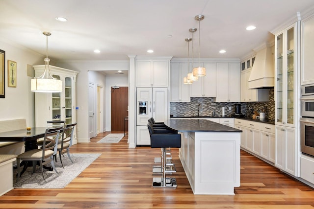 kitchen featuring a center island, light hardwood / wood-style floors, decorative light fixtures, and ornamental molding