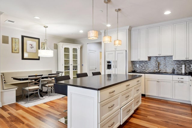 kitchen featuring light hardwood / wood-style floors, white cabinetry, hanging light fixtures, and sink