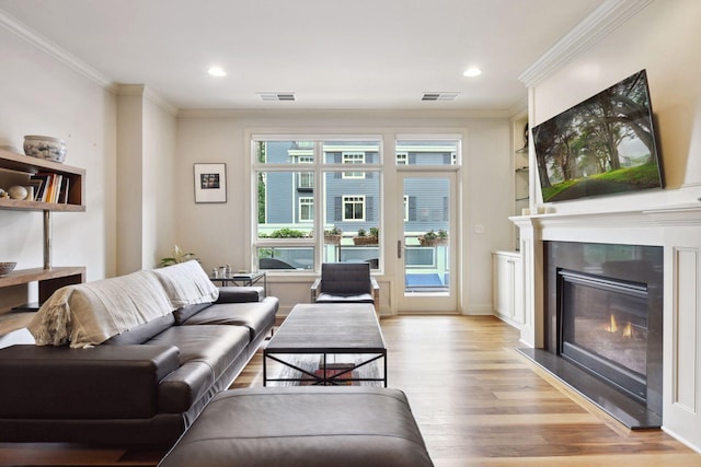 living room featuring light hardwood / wood-style floors, built in features, and ornamental molding