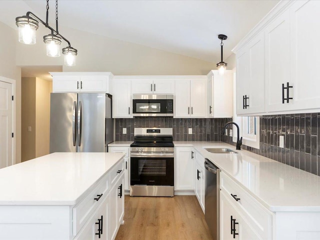 kitchen with sink, a center island, backsplash, lofted ceiling, and appliances with stainless steel finishes