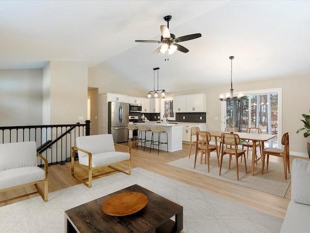 living room with lofted ceiling, sink, ceiling fan with notable chandelier, and light hardwood / wood-style flooring