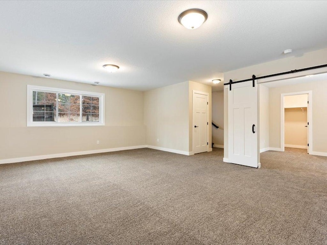 unfurnished bedroom with a barn door, a closet, and carpet