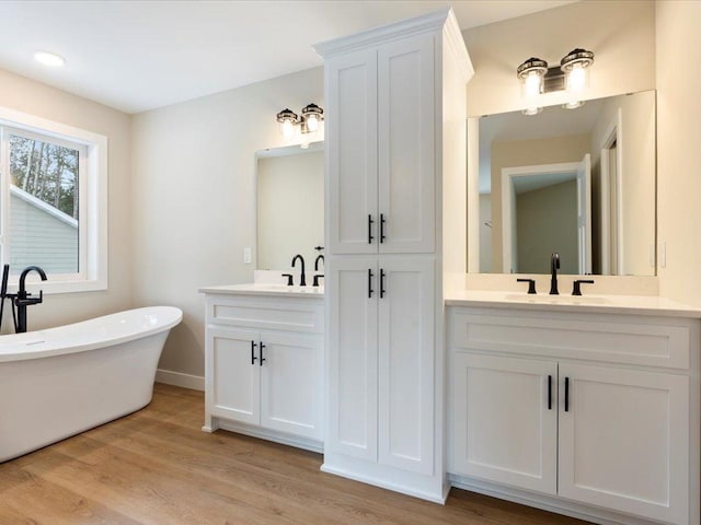 bathroom with hardwood / wood-style floors, vanity, and a tub