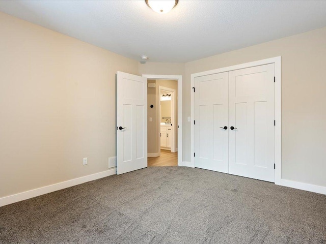 unfurnished bedroom with a closet, baseboards, and carpet flooring