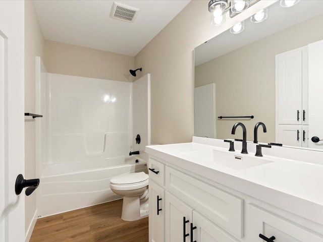 full bathroom featuring visible vents, toilet, wood finished floors, vanity, and shower / washtub combination