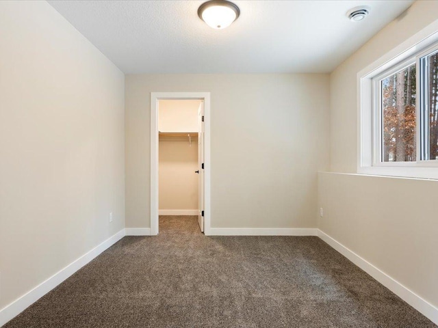 empty room featuring carpet flooring, visible vents, and baseboards