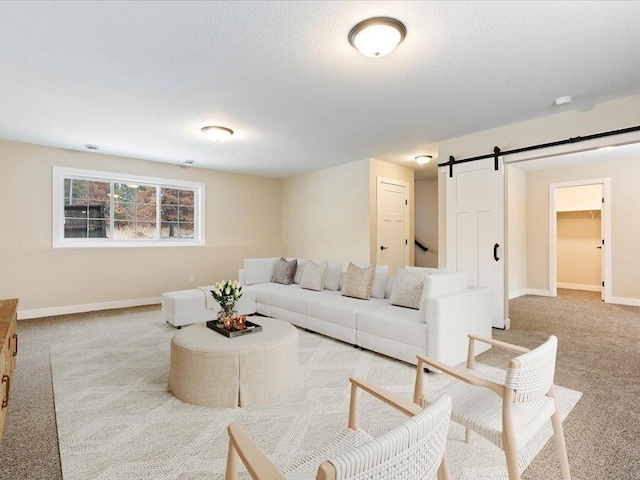 carpeted living room with a barn door, baseboards, and a textured ceiling