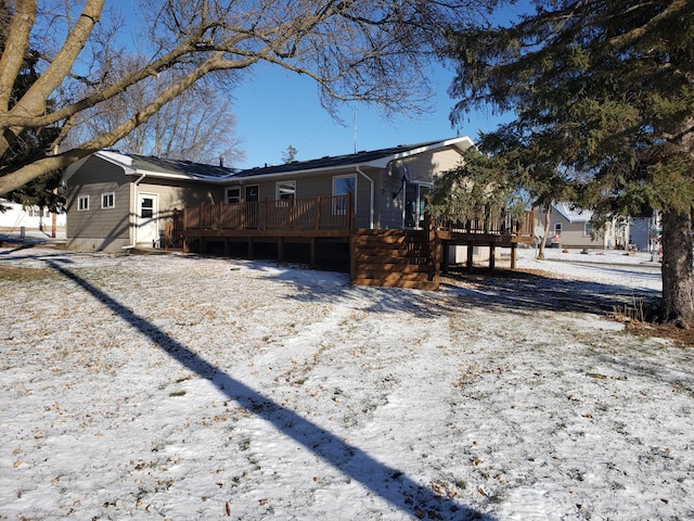 snow covered back of property featuring a deck