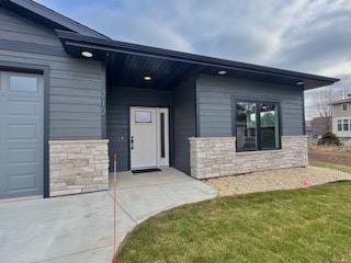 doorway to property featuring a garage and a lawn